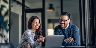 Smiling brunette girl, showing something online to her boss.