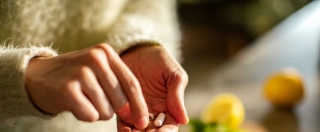 Close up of a Young woman taking a health supplement in the kitchen.