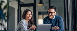 Smiling brunette girl, showing something online to her boss.