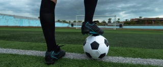 Soccer player foot on top of soccer ball.