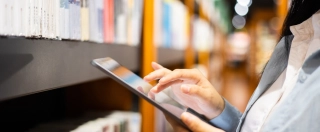 Women using digital tablet in library.
