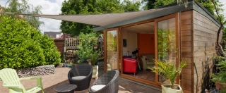 Garden room with patio furniture and sun shade.