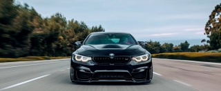 Black BMW M4 driving on the street without any other cars around.