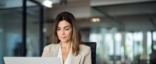Busy mature middle aged professional business woman manager executive looking at laptop computer technology in office working on digital financial banking market sitting at desk. Copy space.