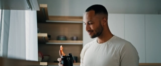 African strong healthy sports man male sport athlete bodybuilder trainer guy in kitchen smile drinking liquid calcium vitamins dietary supplements clean water protein aqua with plastic fitness bottle.