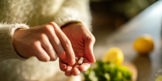 Close up of a Young woman taking a health supplement in the kitchen.